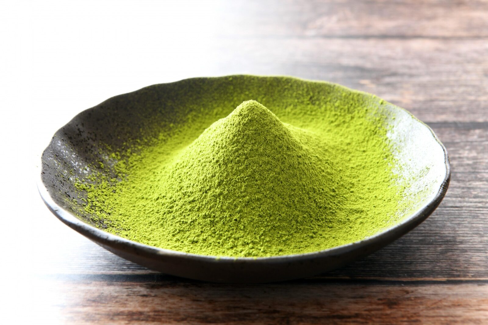 Fine green matcha powder on a dark ceramic plate